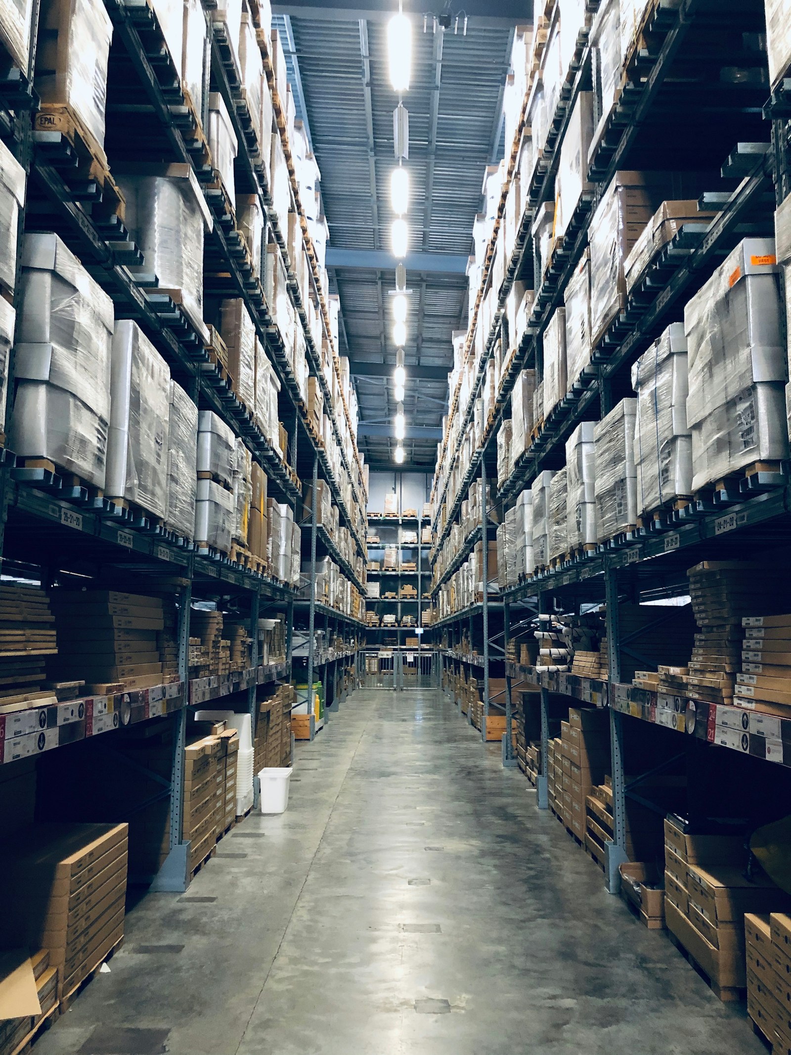 大型物流仓库中高耸的货架长廊,堆满成箱货物——示意把多品类需求拼成一票、摊薄固定成本的整合思路。